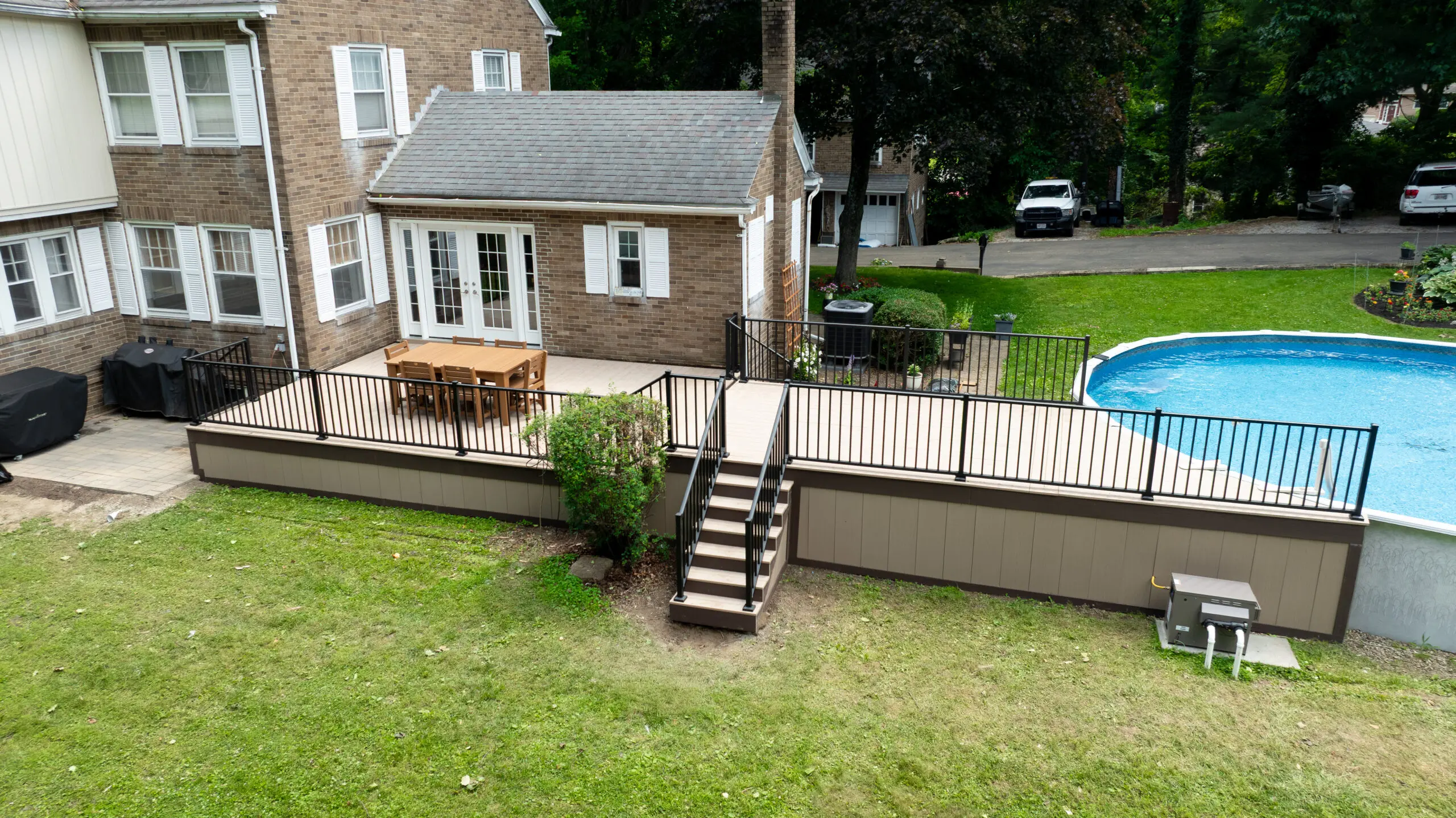 Composite deck with black railing and stairs beside an above-ground pool