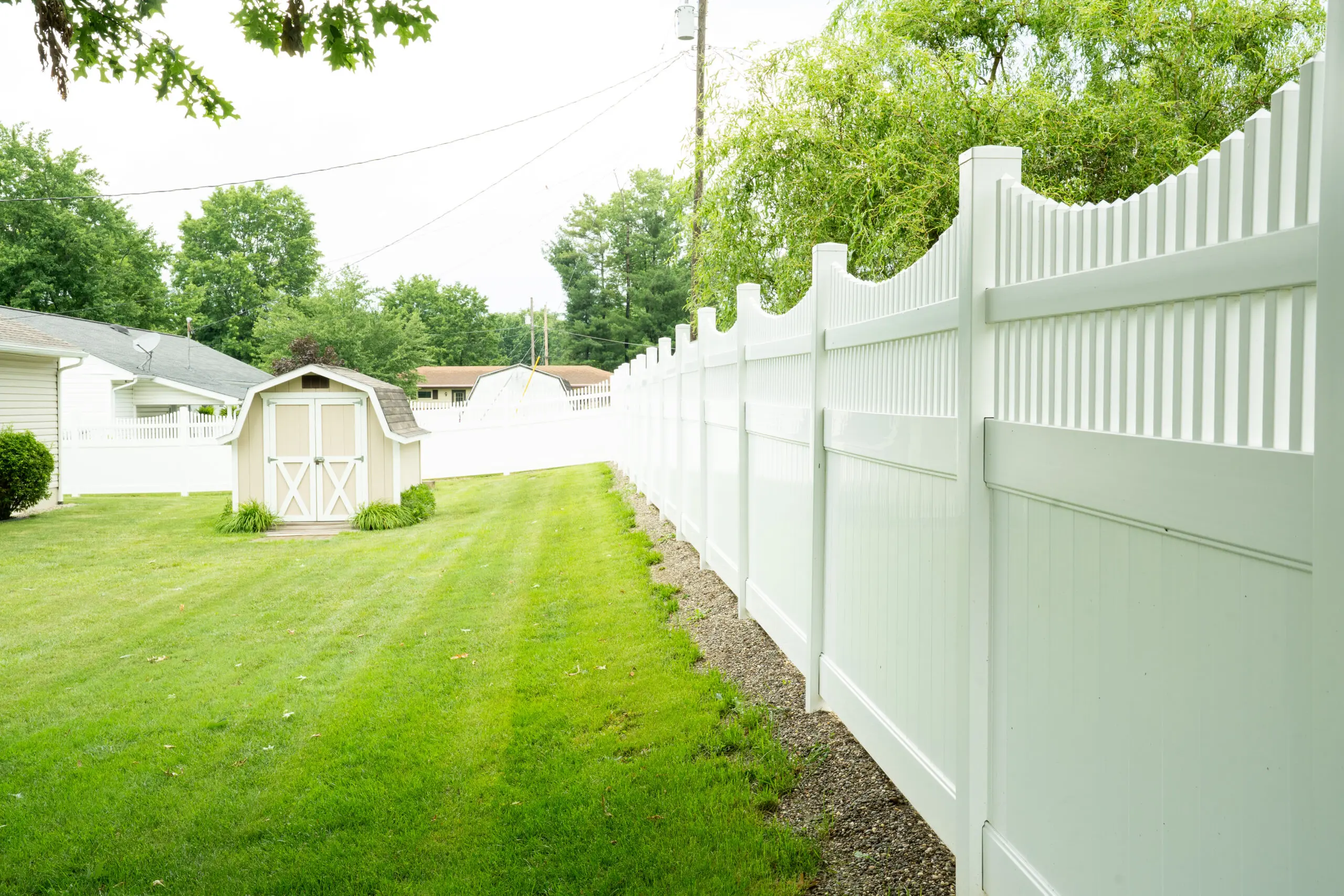 White vinyl privacy fence along a backyard lawn