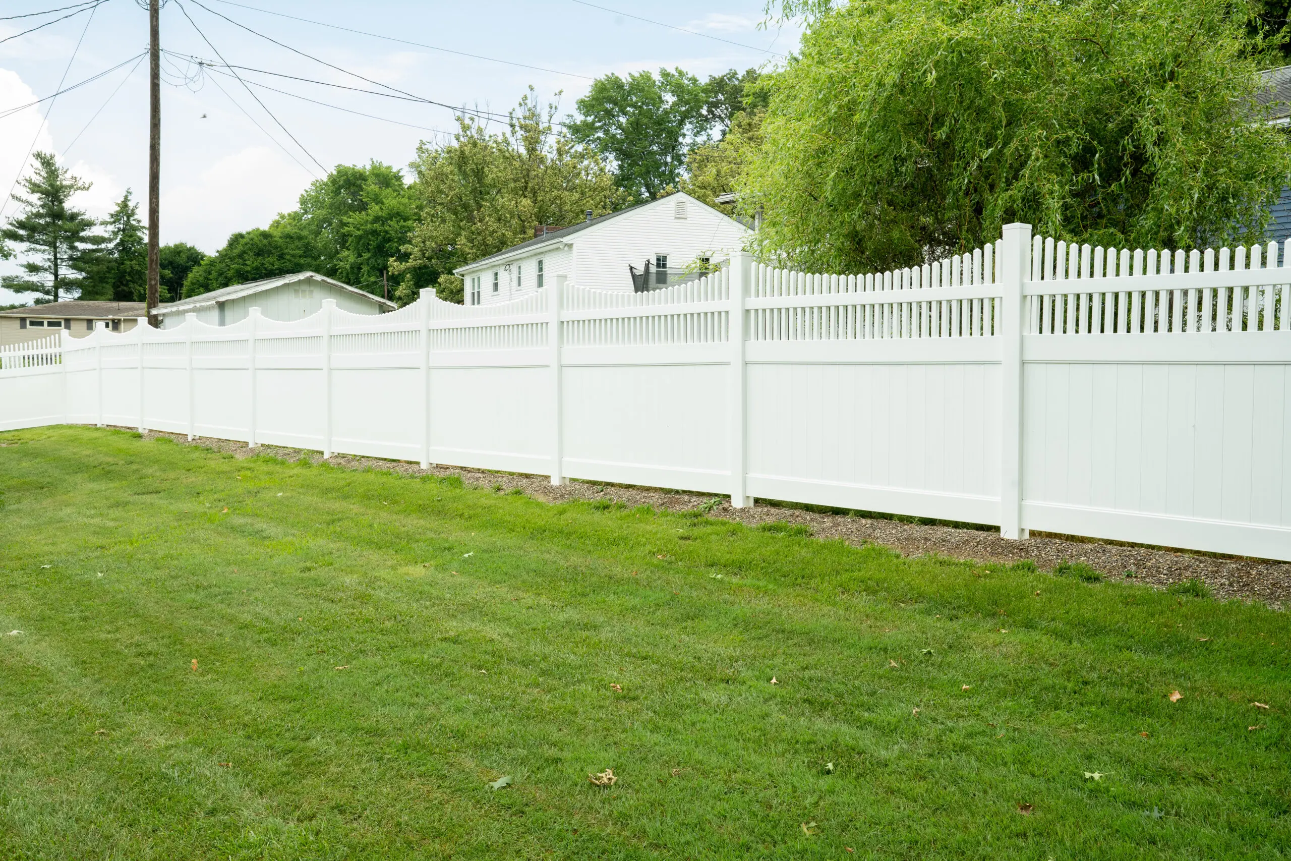 White vinyl privacy fence along a mown lawn