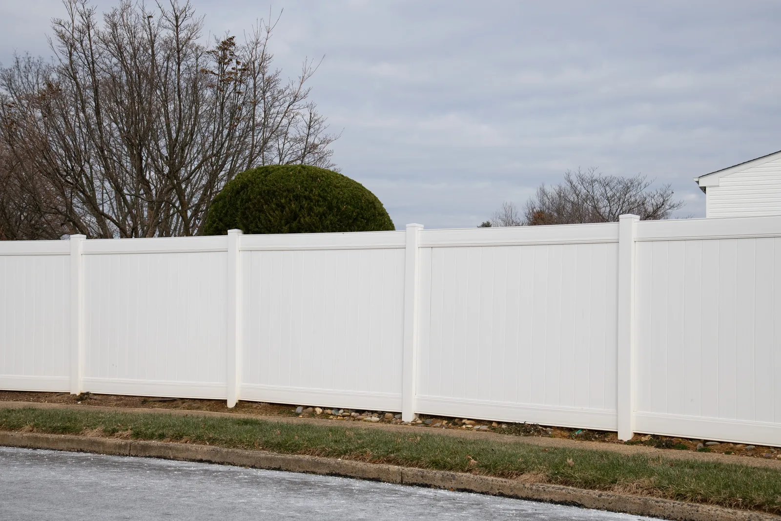 White vinyl privacy fence along a lawn on an overcast day