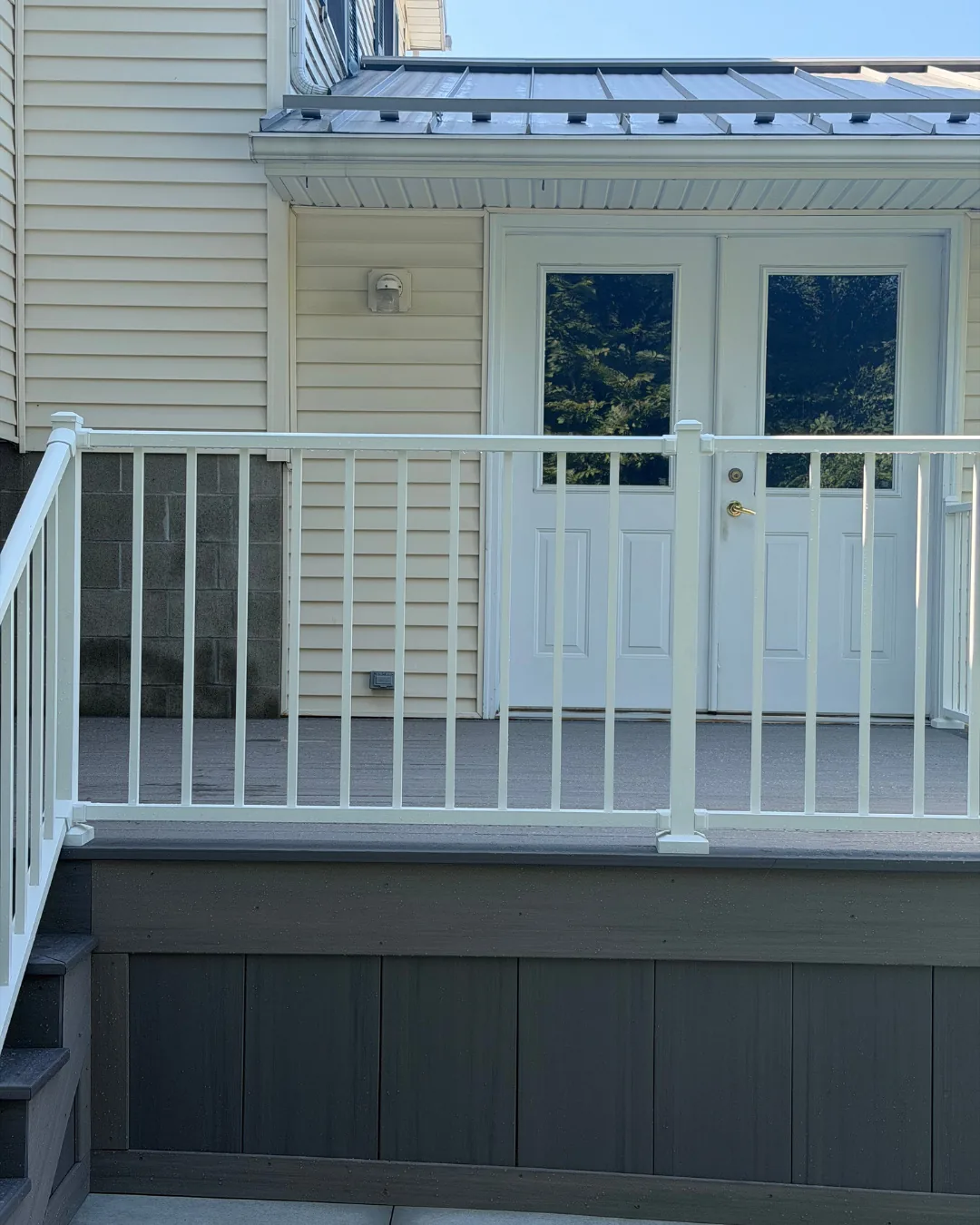 White aluminum railing on a gray composite deck in front of white French doors