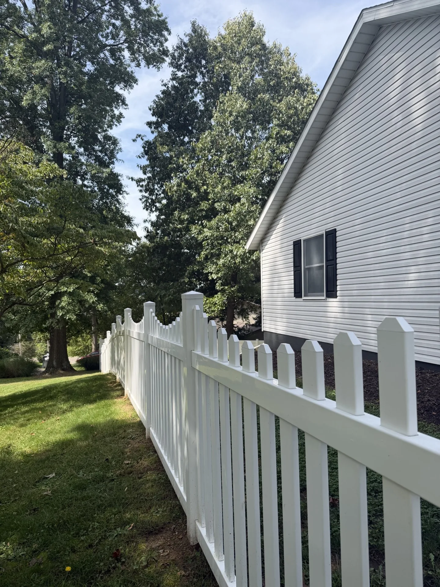 White picket fence running along the side of a gray-sided house