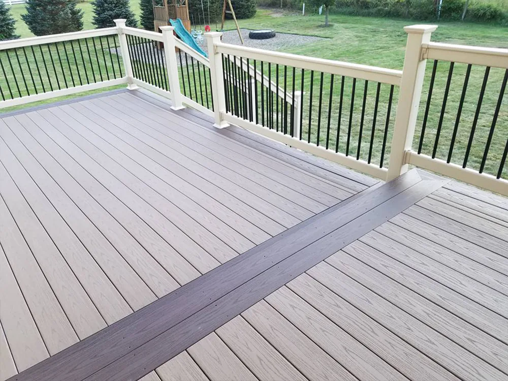 Grey composite deck boards with white and black railing overlooking a backyard