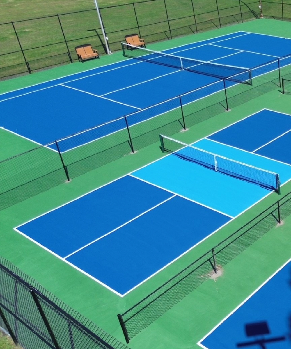 Black chain-link fencing surrounding blue and green outdoor sports courts
